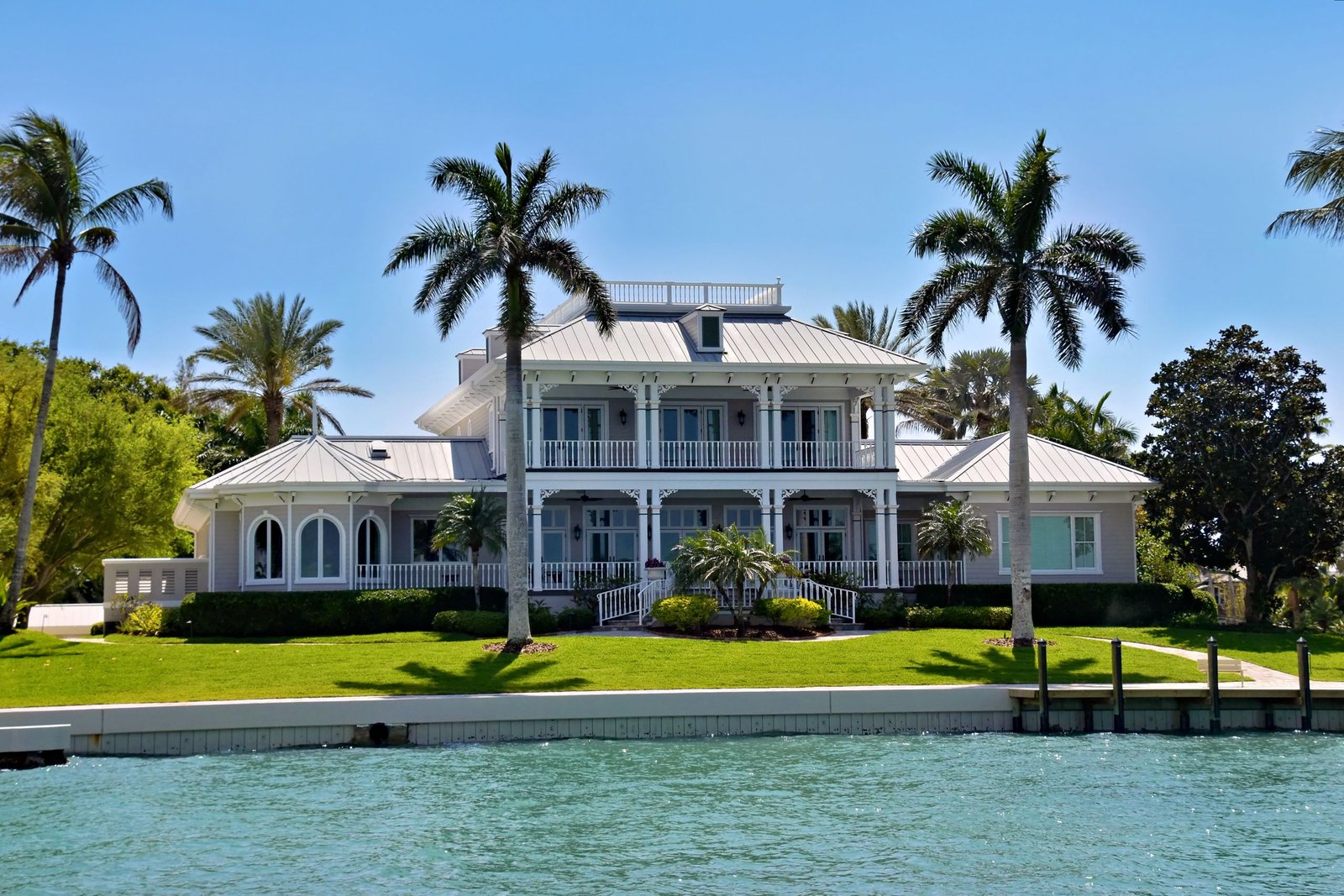 Lawn Mowing Elegant waterfront villa with palm trees and lush greenery, ideal for luxury living.